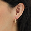 Gold hoop earrings worn by a person with dark hair.