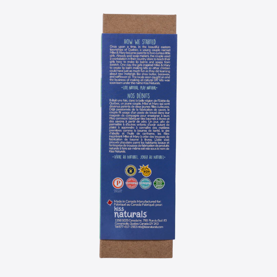 A cardboard box containing a Kiss Naturals Bath Bomb Kit. The box is green and white with the product name and a colorful illustration of bath bombs. It states that the kit is 100% natural, made in Canada, and suitable for ages 6 and up.