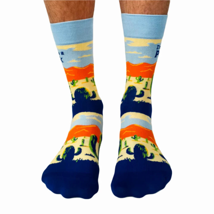 A pair of crew socks with a desert scene and the text 