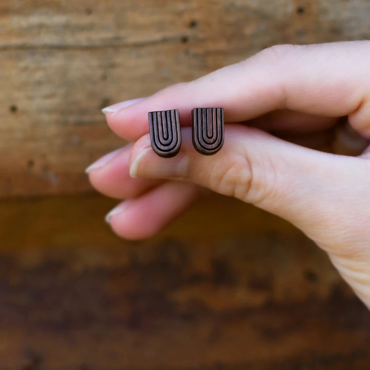 A pair of wooden earrings shaped like rainbows.