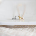 Silver and gold dachshund-shaped earrings on a white surface.