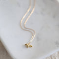 Gold necklace with a small pendant on a marble surface