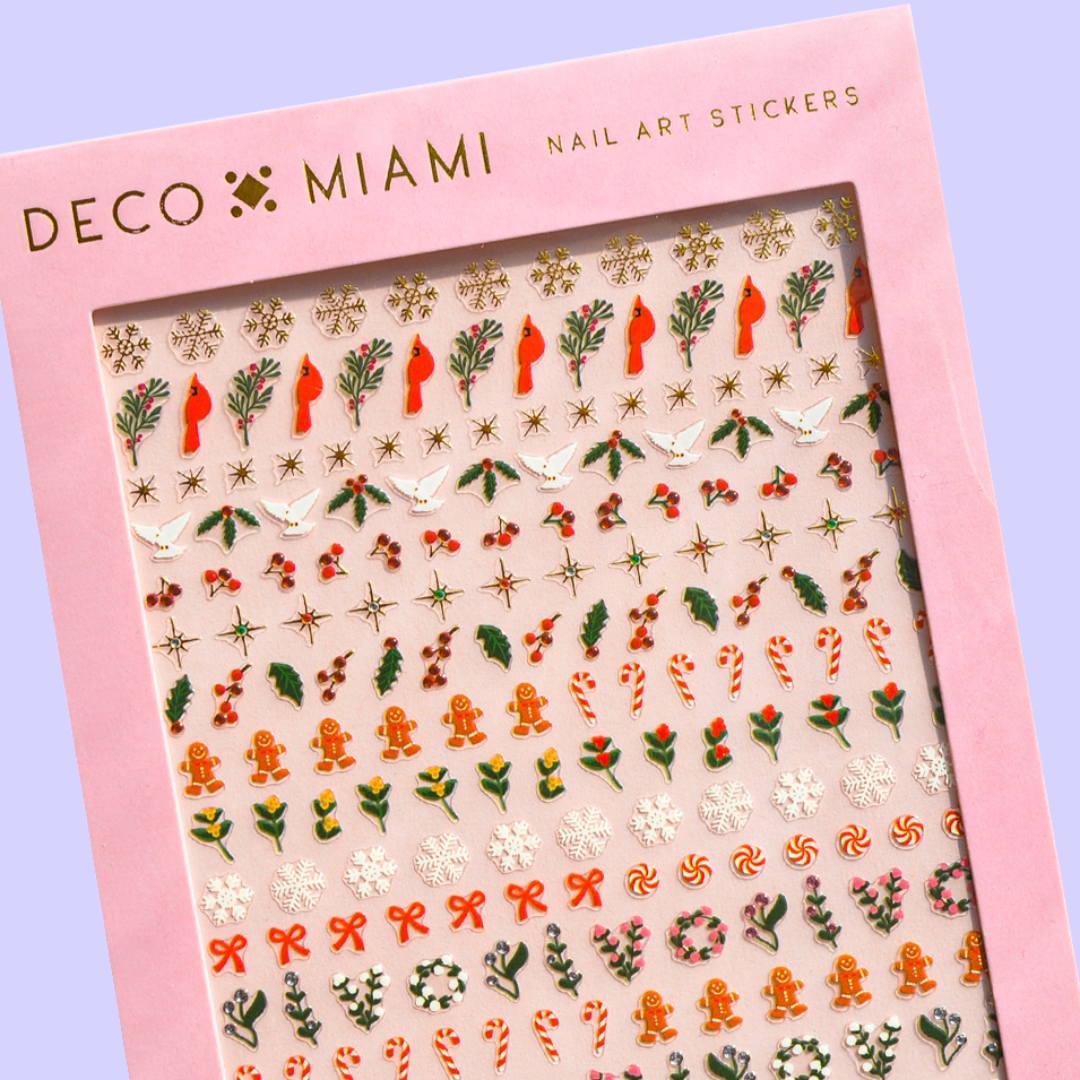 A sheet of Christmas-themed nail art stickers. The sheet is pink and has the brand name "Deco Beauty" printed on it. There's a section titled "Deco the Halls" and instructions on how to apply the stickers. The stickers include various Christmas-themed designs like snowflakes, bells, ornaments, and candy canes.