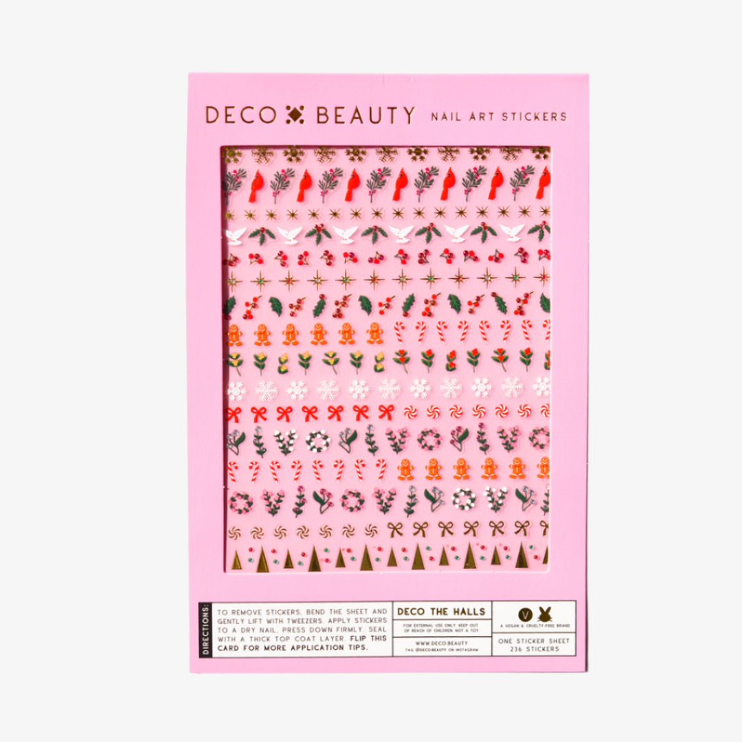 A sheet of Christmas-themed nail art stickers. The sheet is pink and has the brand name "Deco Beauty" printed on it. There's a section titled "Deco the Halls" and instructions on how to apply the stickers. The stickers include various Christmas-themed designs like snowflakes, bells, ornaments, and candy canes.