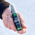 Hand holding a bottle of Bush beard oil against a snowy background