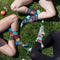 A pair of dark blue women's crew socks with a vibrant, abstract floral pattern in shades of orange, yellow, pink, fuchsia, green, and light blue. Text on one sock reads 
