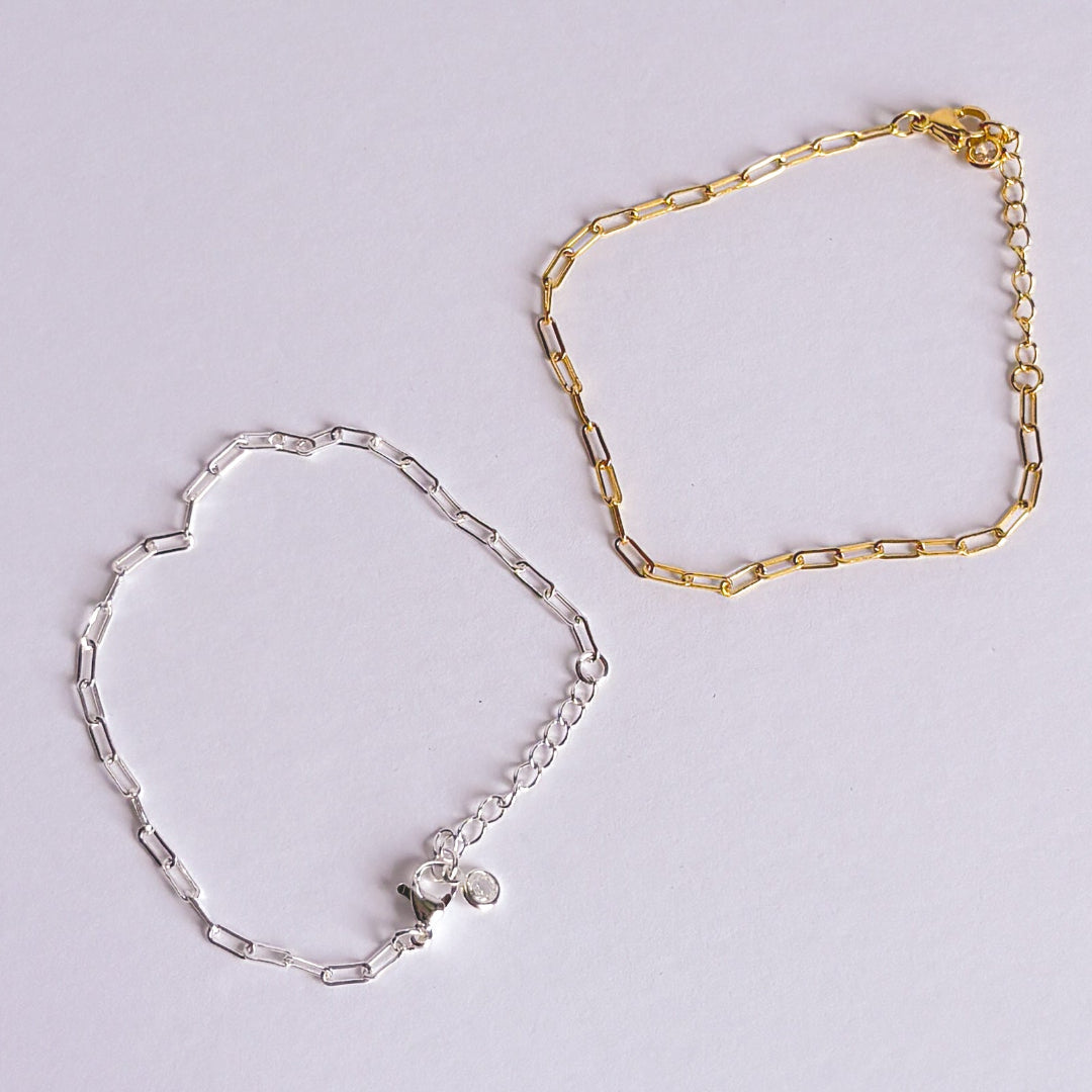 Gold and silver chain bracelets on a light gray background