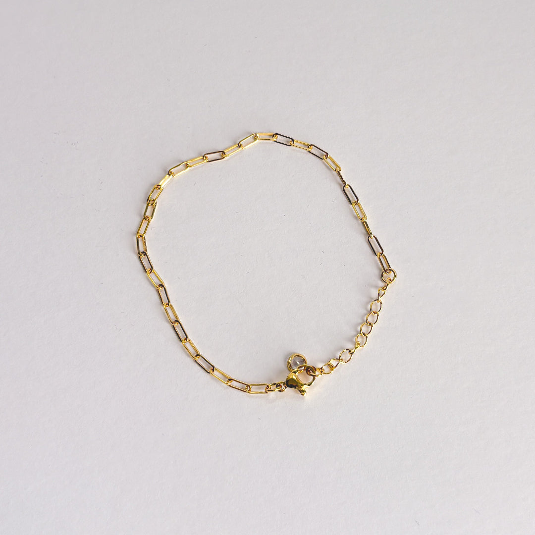 Gold chain bracelet on a light gray background