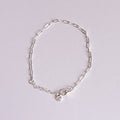 Silver bracelet with a small charm on a light gray background