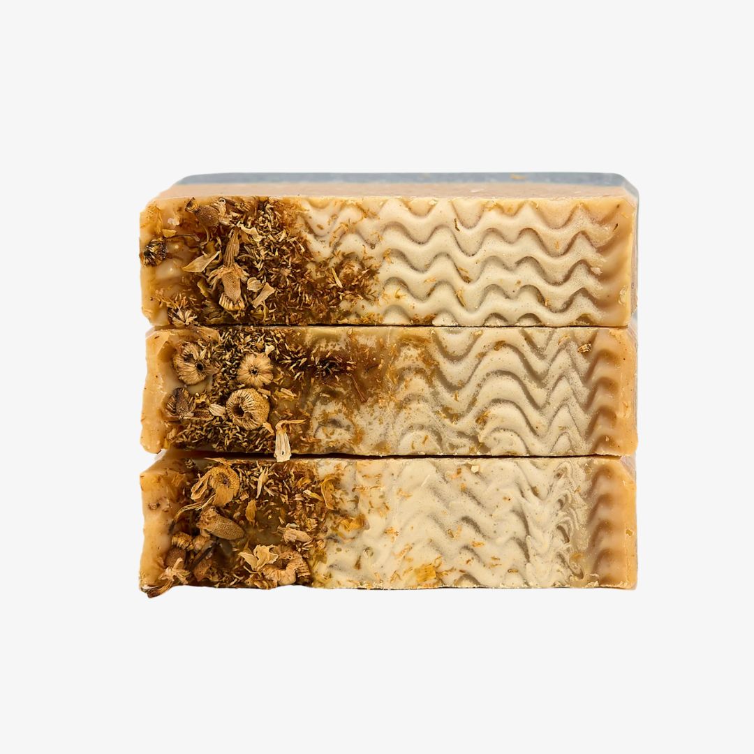 Three bars of soap with different textures and patterns stacked on a white background