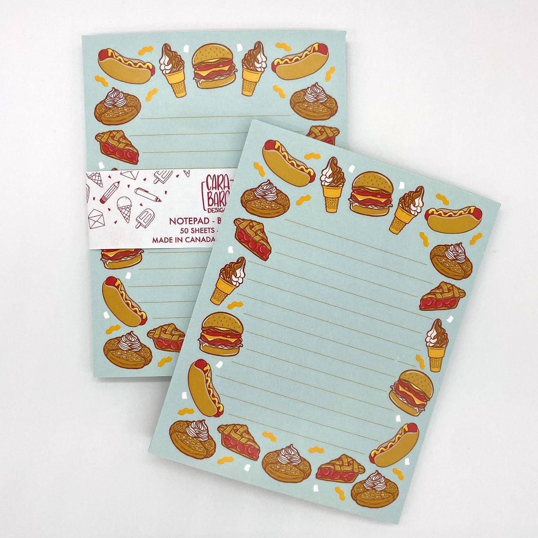 Two notepads with food-themed illustrations on a light blue background, with a visible brand label.