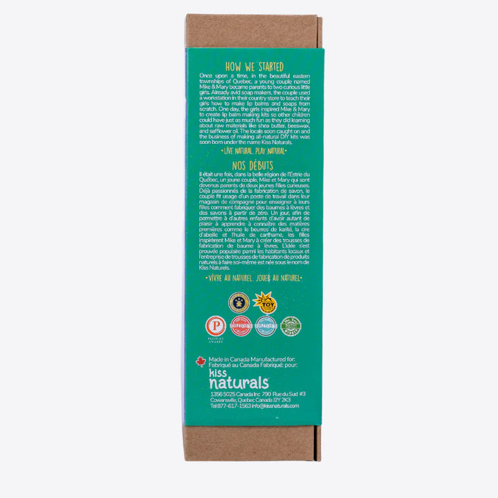 A cardboard box containing a Kiss Naturals Glycerin Soap Kit. The box is blue and white with the product name and a colorful illustration of penguins. It states that the kit is 100% natural, made in Canada, and suitable for ages 6 and up.