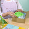 A cardboard box containing a Kiss Naturals Glycerin Soap Kit. The box is blue and white with the product name and a colorful illustration of penguins. It states that the kit is 100% natural, made in Canada, and suitable for ages 6 and up.