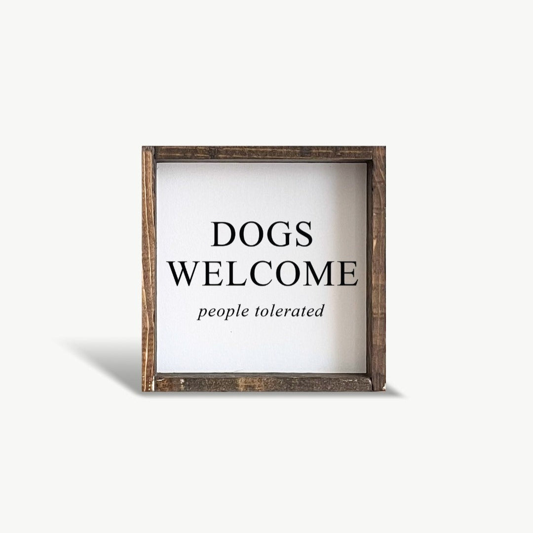 Framed sign with 'DOGS WELCOME people tolerated' text on a white background