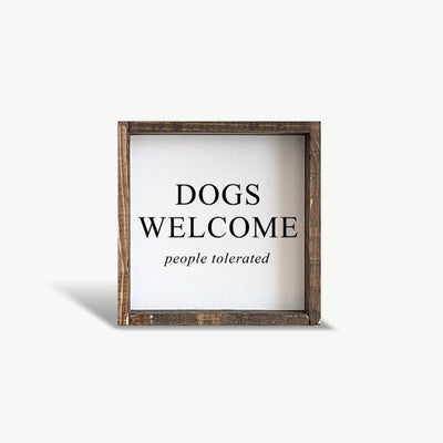 Framed sign with 'DOGS WELCOME people tolerated' text on a white background