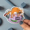 A cartoon illustration of a panicked orange cat surrounded by everyday objects like a vase, incense sticks, a cucumber, and a hairbrush. The text 