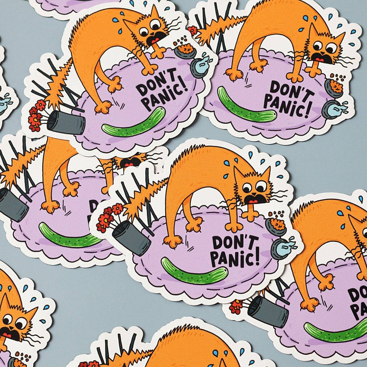 A cartoon illustration of a panicked orange cat surrounded by everyday objects like a vase, incense sticks, a cucumber, and a hairbrush. The text 
