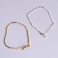 Gold and silver anklets on a light gray background