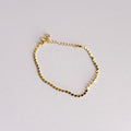 Gold bracelet on a light gray background