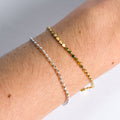 Two bracelets on a wrist against a neutral background