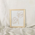 Framed artwork with minimalist line art of leaves on a light background