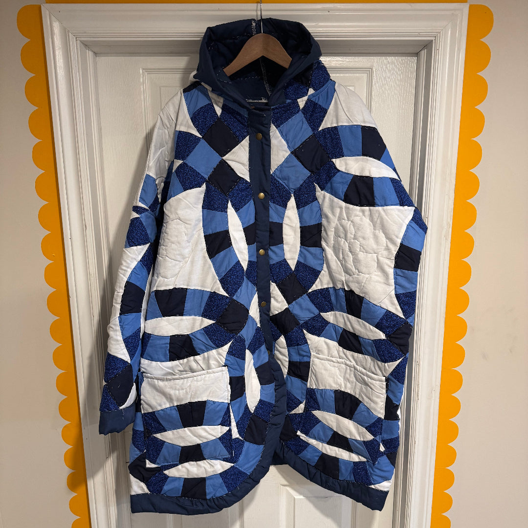 A hooded quilt jacket featuring blue and white Double Wedding Ring quilt patterns, hanging on a white paneled door framed by a yellow scalloped border.

If you’d like a more romantic, minimalist, or bold tone, I can shape the description however you like.