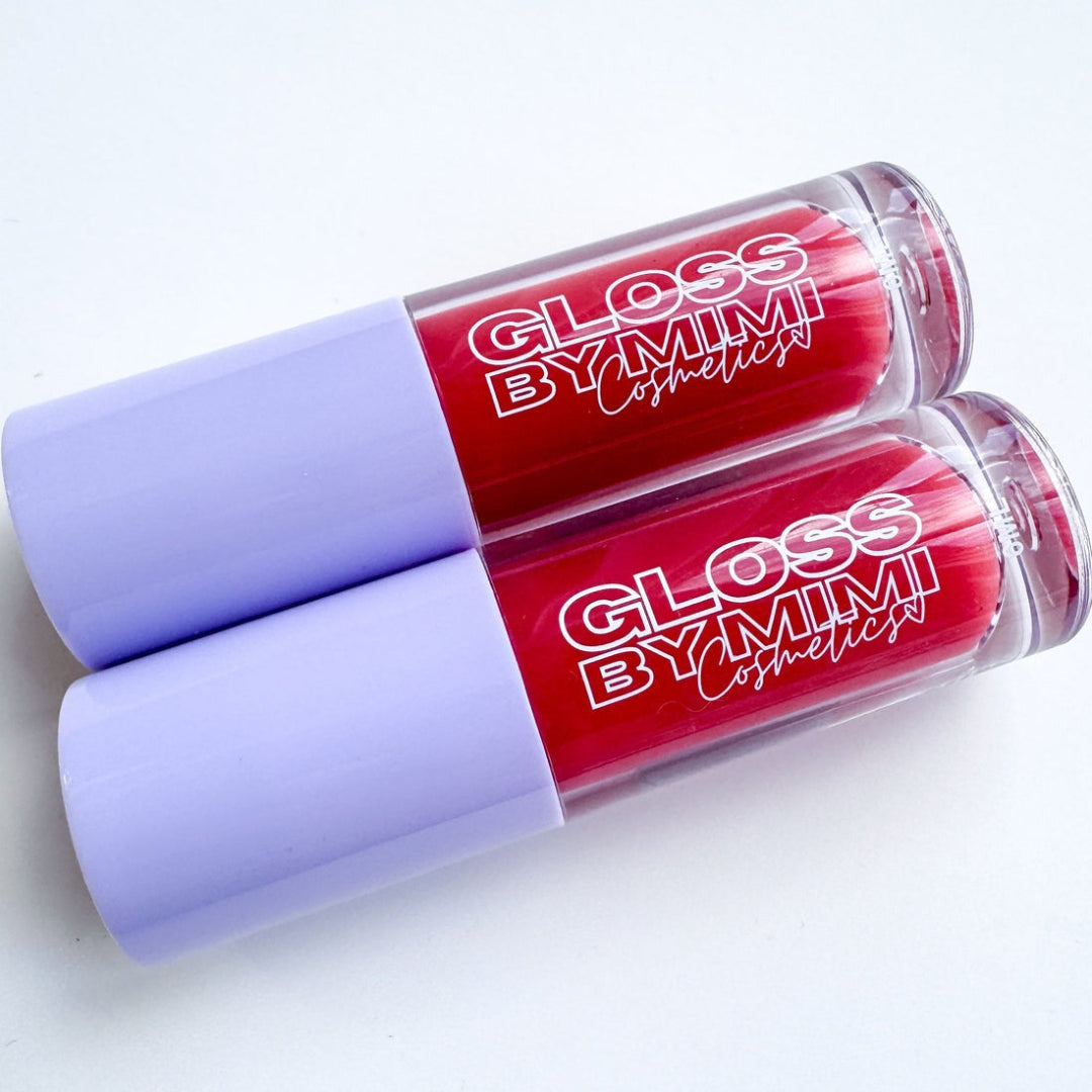 Two red lip glosses with purple caps on a white background, featuring 'Gloss by Mimi' branding.