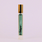 A small, cylindrical bottle of perfume with a gold cap. The bottle is transparent and filled with a light-colored liquid. The label on the bottle reads 