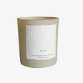 A beige glass jar candle with a white label. The label reads "NORTH ROSE" and "DREAM." 
