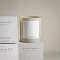 A beige glass jar candle with a white label. The label reads "NORTH ROSE" and "DREAM." 