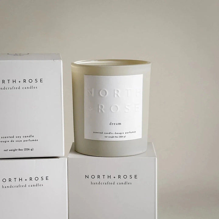A beige glass jar candle with a white label. The label reads 