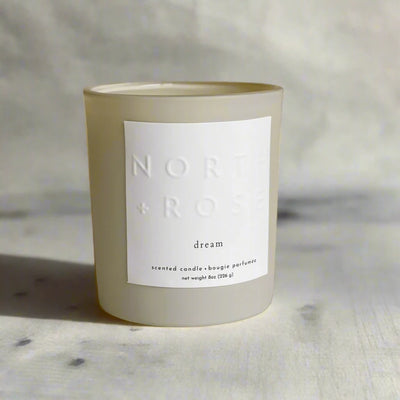A beige glass jar candle with a white label. The label reads 