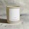 A beige glass jar candle with a white label. The label reads 