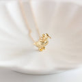 Gold duck-shaped pendant on a chain against a light background