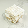A square marshmallow with swirls of white and brown. The marshmallow is resting on a white marble surface.