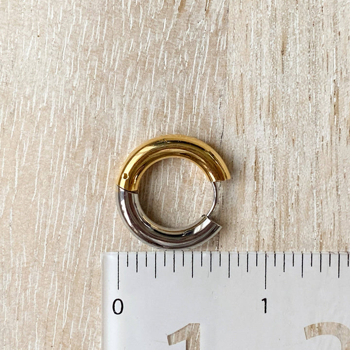 Two-tone chunky hoop huggie earrings (gold and silver) by agaveh girl, displayed on a branded card with the text 'agaveh girl,' against a textured background. The earrings are 4mm thick, made of stainless steel, and are sold in Ottawa, Ontario, Canada