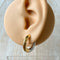 Two-tone chunky hoop huggie earrings (gold and silver) by agaveh girl, displayed on a branded card with the text 'agaveh girl,' against a textured background. The earrings are 4mm thick, made of stainless steel, and are sold in Ottawa, Ontario, Canada