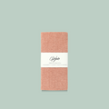 A coral-colored Swedish dishcloth. The dishcloth has a textured surface and is labeled "Goldilocks Swedish Dishcloth" with information about its compostability, reusability, and machine washability.