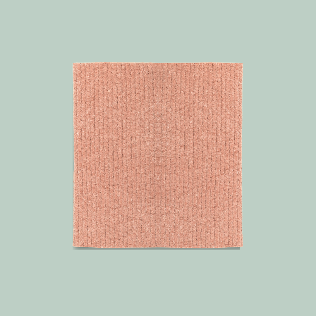 A coral-colored Swedish dishcloth. The dishcloth has a textured surface and is labeled "Goldilocks Swedish Dishcloth" with information about its compostability, reusability, and machine washability.