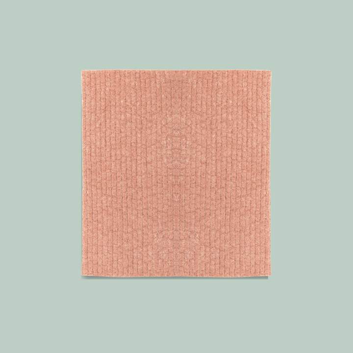 A coral-colored Swedish dishcloth. The dishcloth has a textured surface and is labeled 