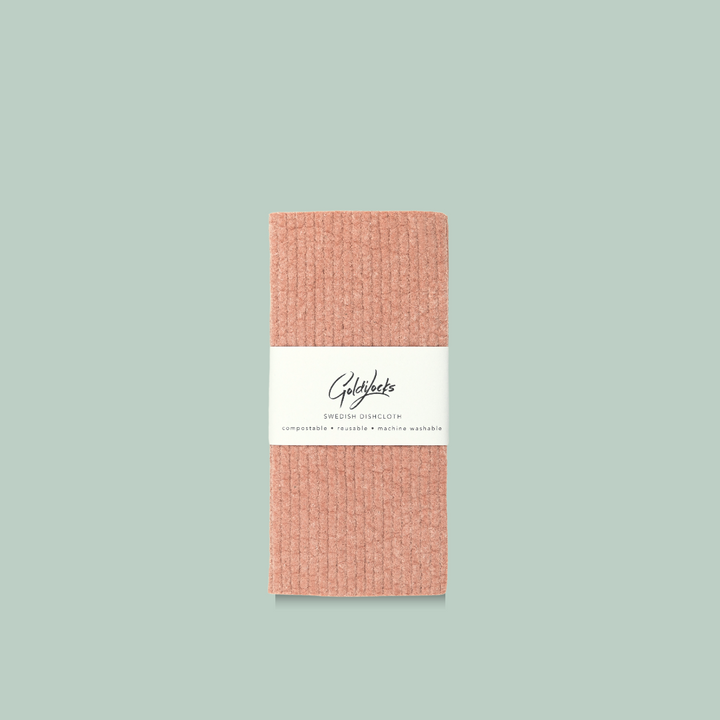 A coral-colored Swedish dishcloth. The dishcloth has a textured surface and is labeled 