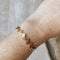 A gold-toned bangle bracelet with a row of circular discs. 