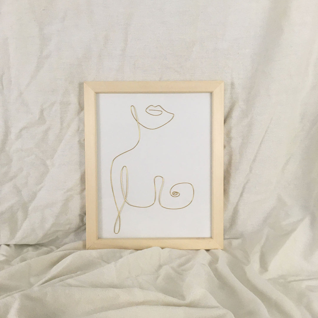 Framed line art of a woman on a beige fabric background