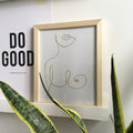 Framed minimalist line art of a woman's silhouette on a wall with motivational quote