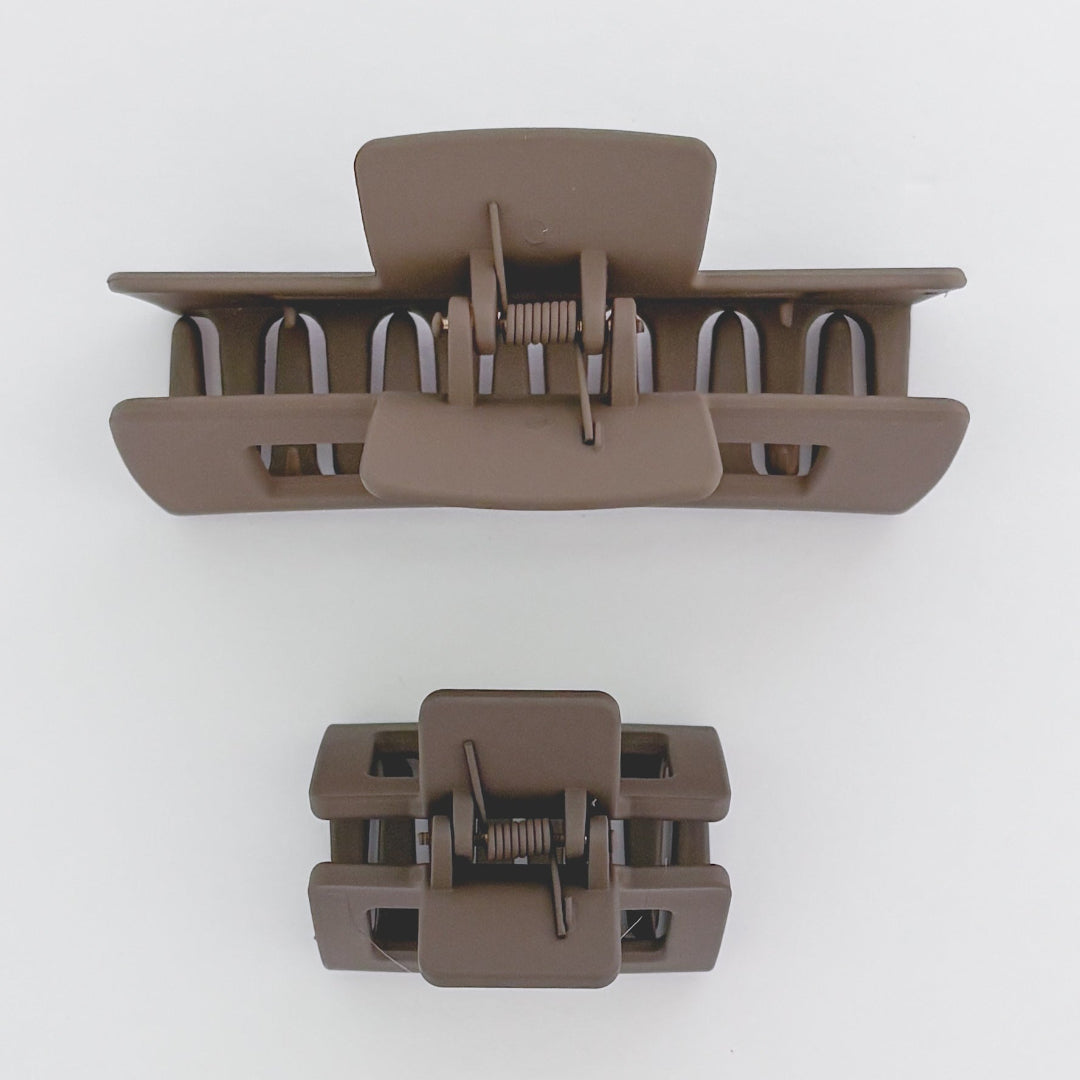 Two brown hair clamps on a white background