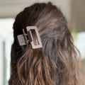 Close-up of a hair tie securing brown hair against a blurred background