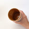 Mountains Travel Mug, a ceramic mug with a matte finish, with a mountain scape around the perimeter. Comes with a blue silicone lid.
