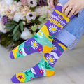 Colorful floral-patterned socks with text held by a person against a floral background