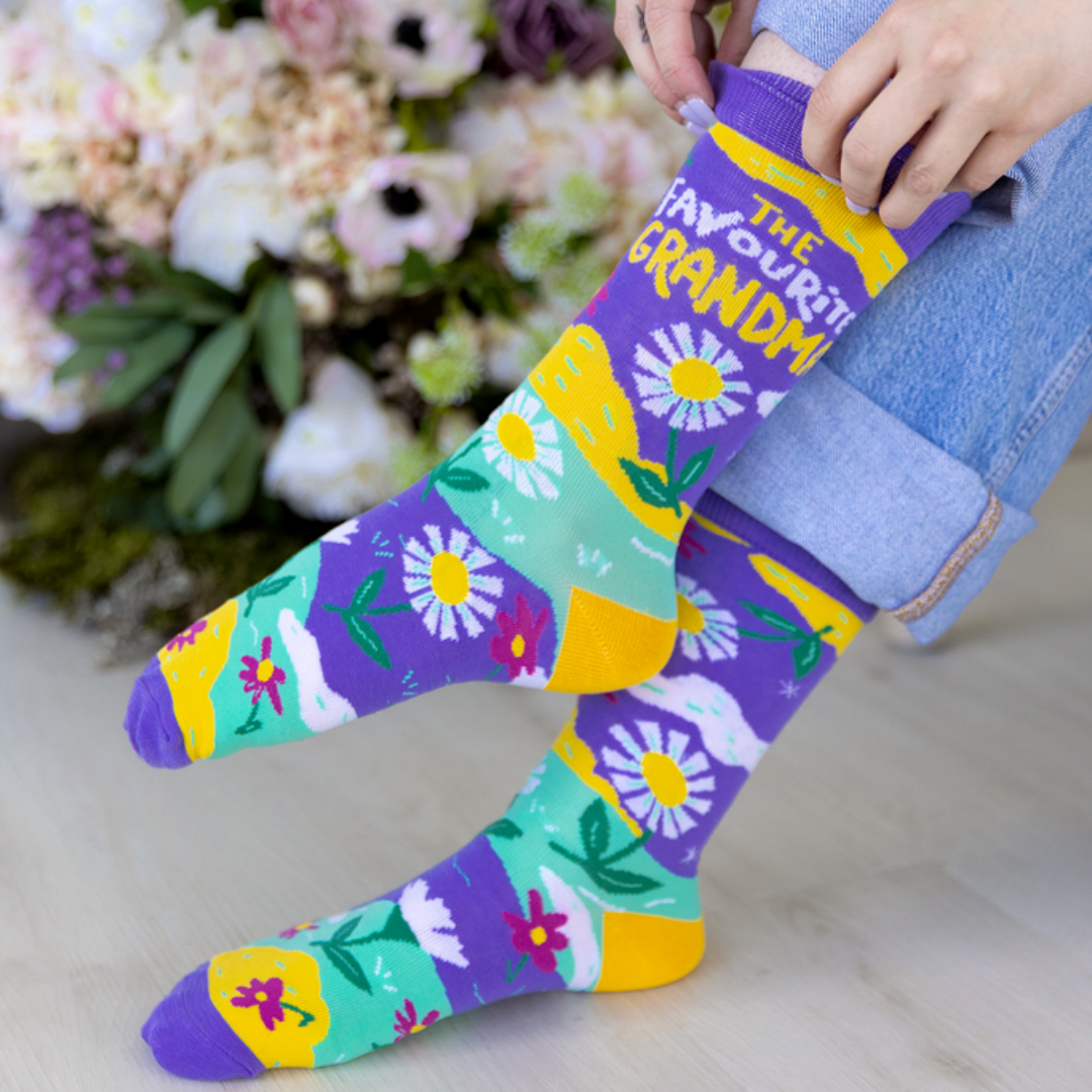 Colorful floral-patterned socks with text held by a person against a floral background
