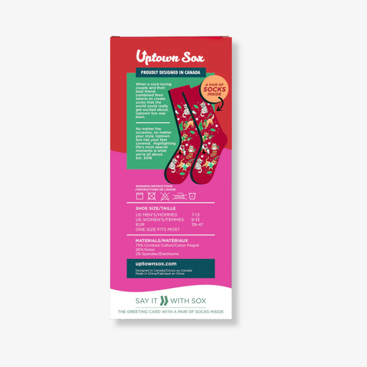 A pair of red socks with a festive cat design, packaged with a card. The socks feature cats playing with Christmas decorations, and the card has the text 